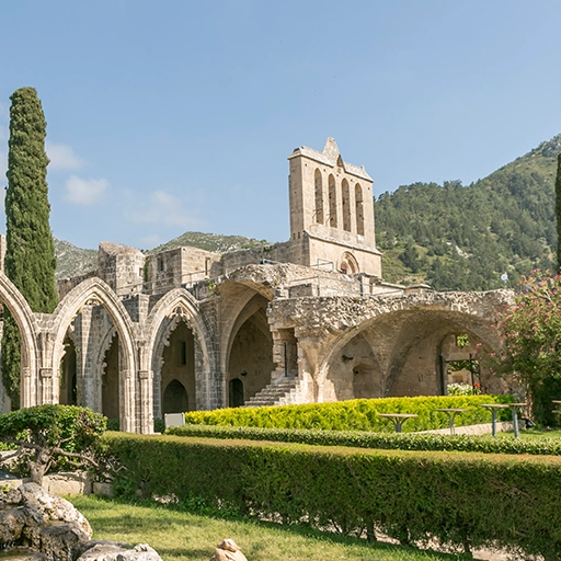 Bellapais manastırında Gotik kemerlerin geniş açılı görünümü, mavi gökyüzü ve altın ışık